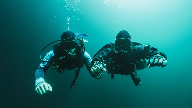 Deux plongeurs explorent les profondeurs marines, équipés et face à la caméra