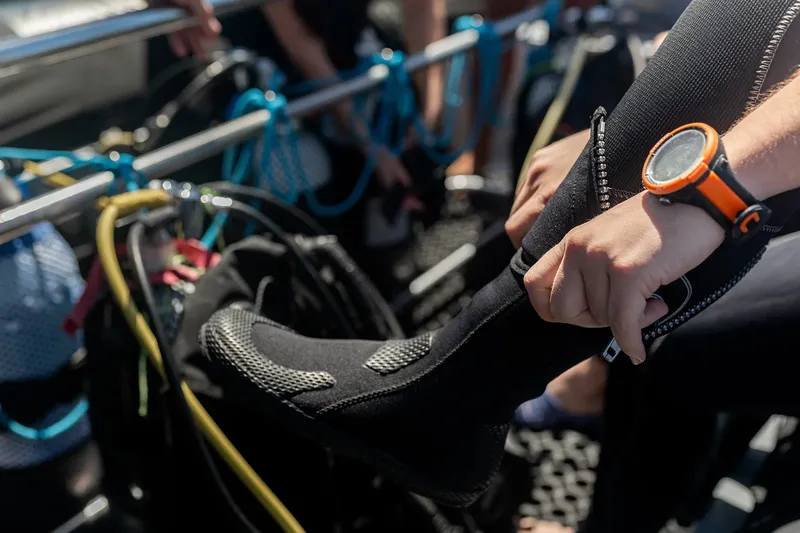 Préparation d'une combinaison de plongée avec une montre orange visible