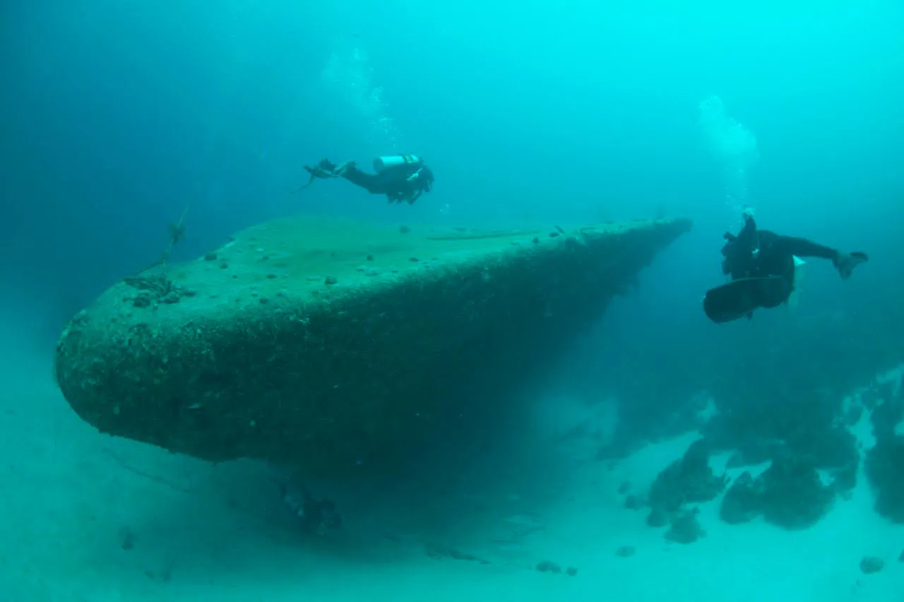 Deux plongeurs explorent l'épave d'un grand navire sous-marin