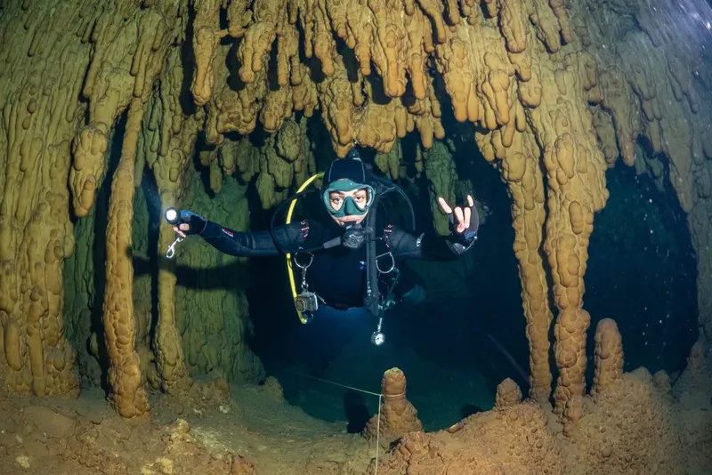 Plongeur explore une grotte sous-marine avec des formations rocheuses impressionnantes