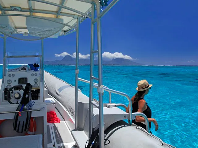 Femme regardant l'horizon depuis un bateau de plongée turquoise