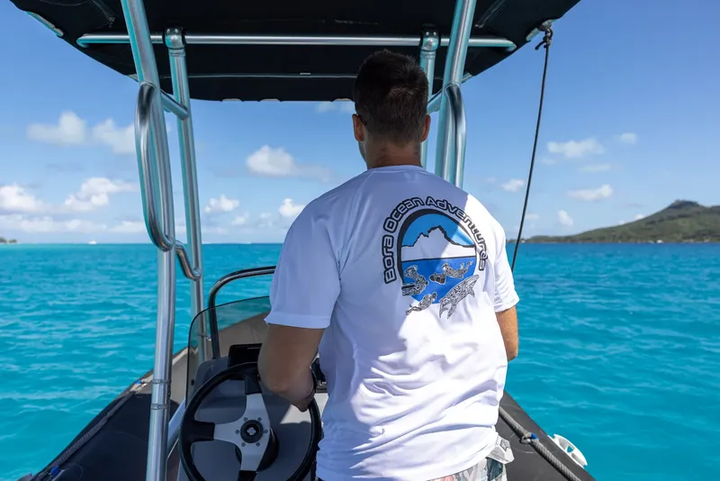 Homme au volant d'un bateau pneumatique sur une eau turquoise