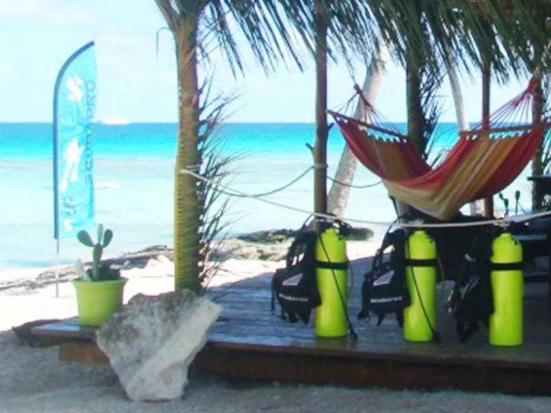 Bouteilles de plongée, hamac et drapeau sur une plage tropicale