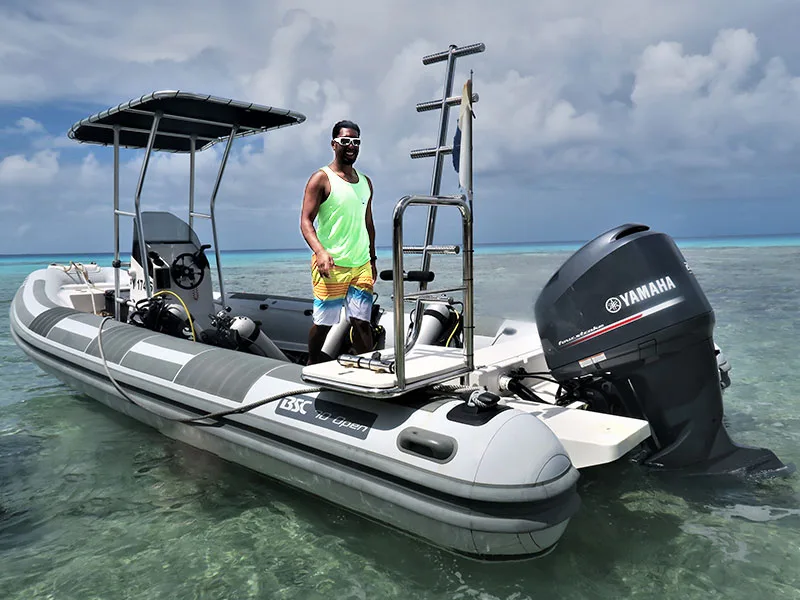 Homme souriant sur un bateau semi-rigide au large d'une plage