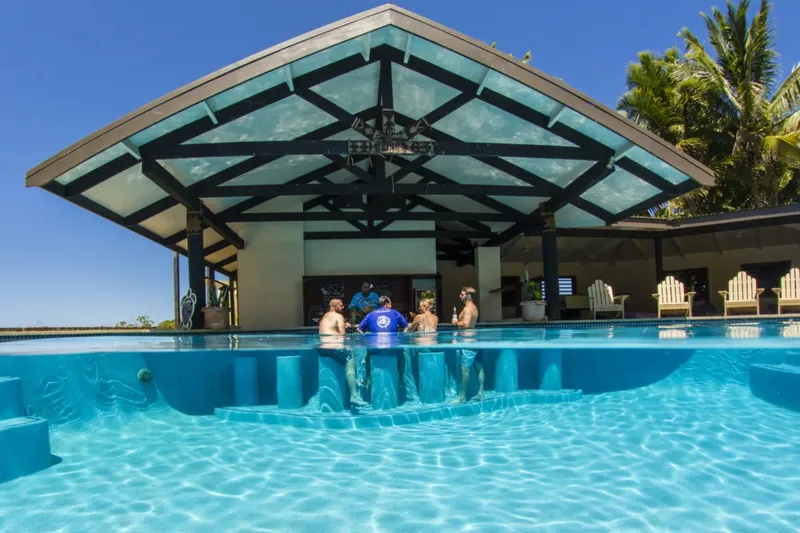 Personnes dans une piscine avec un bar intégré et une structure couverte