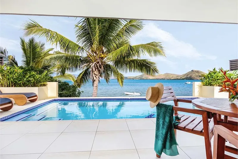 Piscine avec vue sur la mer, palmier et bateaux au loin