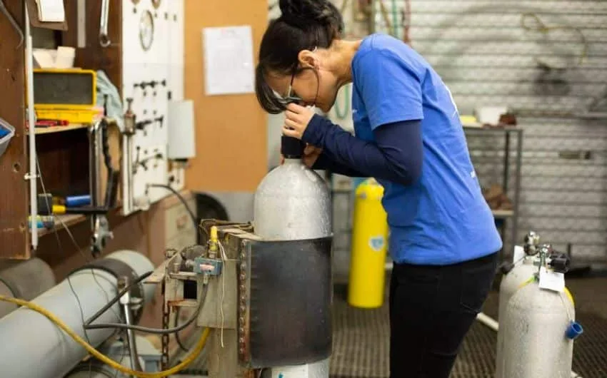 Une personne vérifie une bouteille de plongée avec un outil spécialisé
