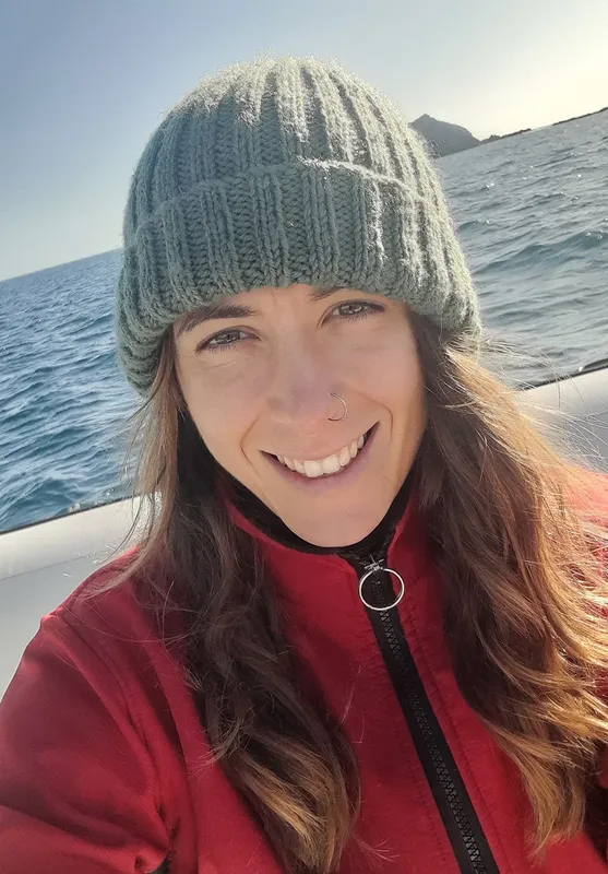 Femme souriante portant un bonnet et une veste rouge en mer