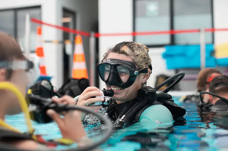 Plongeuse en formation vérifie son équipement dans une piscine intérieure
