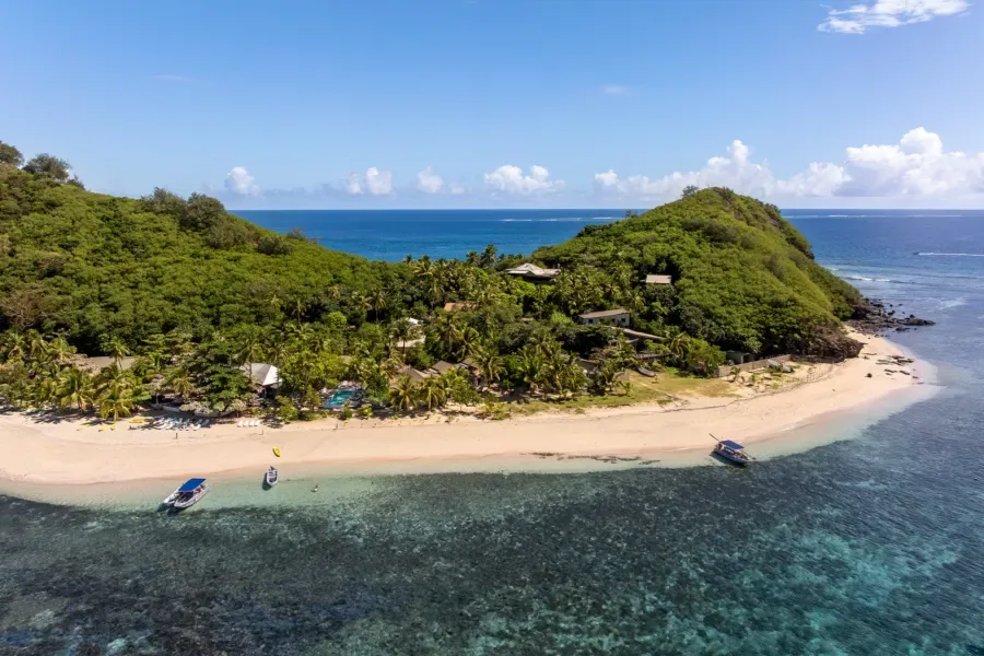 Vue aérienne d'une plage tropicale avec des bateaux et végétation luxuriante