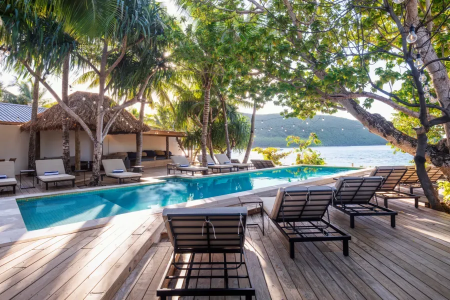 Piscine et transats dans un cadre tropical avec végétation luxuriante