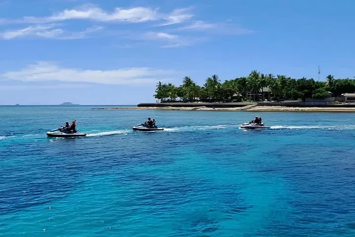 Trois jet-skis naviguent sur une mer turquoise ensoleillée