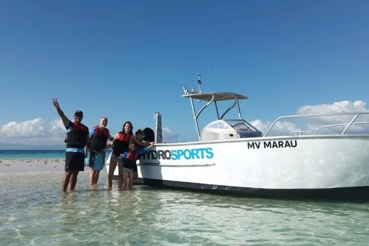 Groupe de personnes souriantes près d'un bateau blanc sur plage
