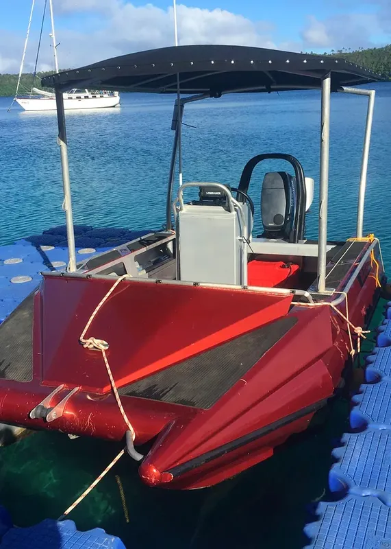 Bateau rouge amarré à un ponton flottant sur une eau turquoise