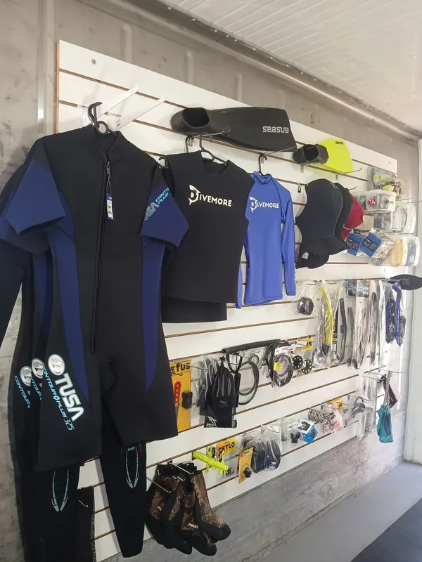 Combinaisons de plongée, masques, palmes et accessoires accrochés au mur d'un magasin