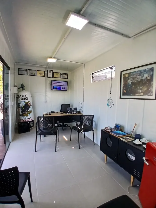Bureau d'accueil lumineux avec ordinateur, chaises et affiches de plongée