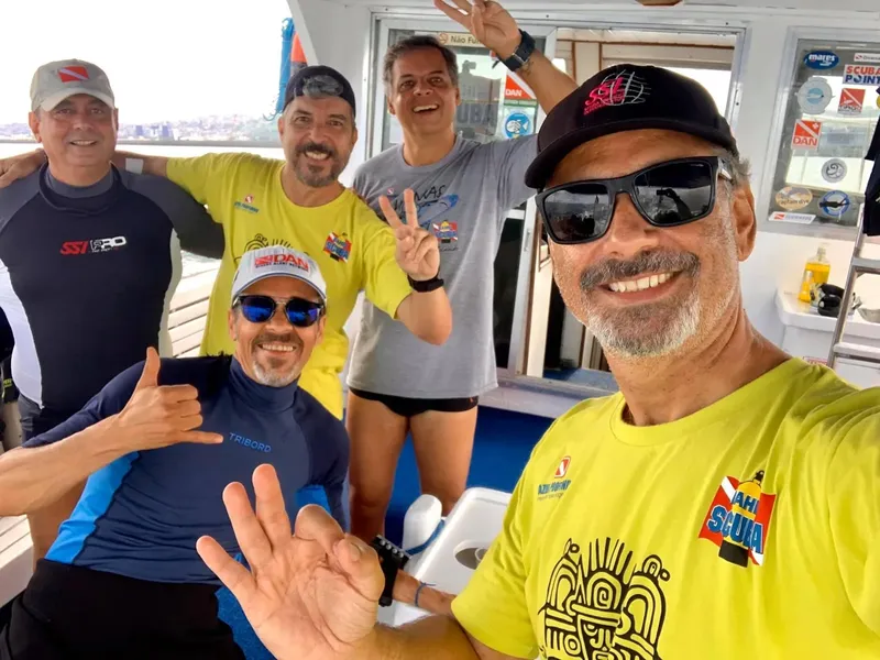Groupe de plongeurs souriants sur un bateau en mer, joie et camaraderie
