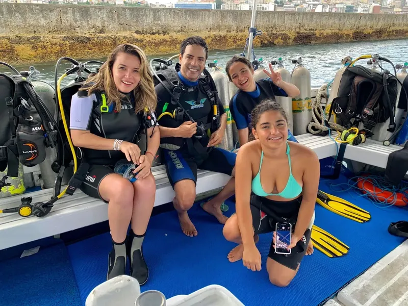 Quatre plongeurs souriants posent sur un bateau avec leur équipement