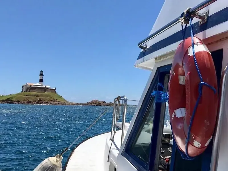 Bateau de plongée en mer avec un phare sur une île rocheuse