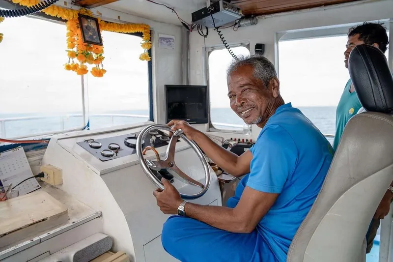 Homme souriant tient le volant d'un bateau en mer