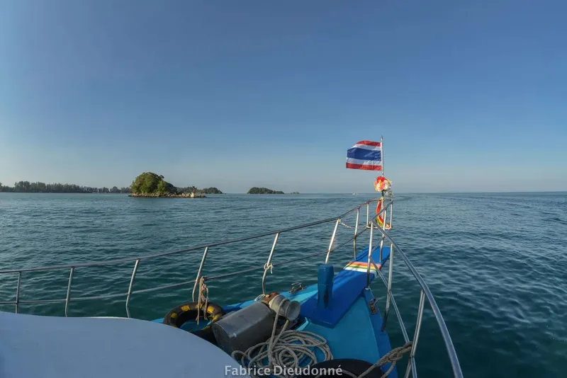 Bateau de plongée en mer avec des îles au loin ciel bleu