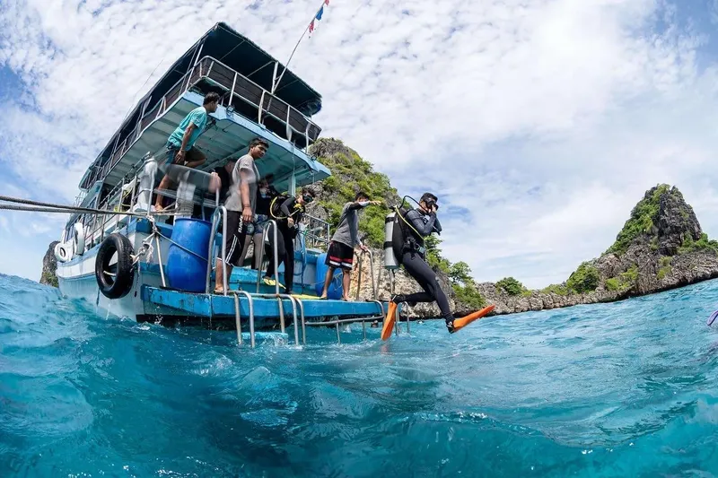 Plongeur s'apprête à sauter d'un bateau bleu en mer