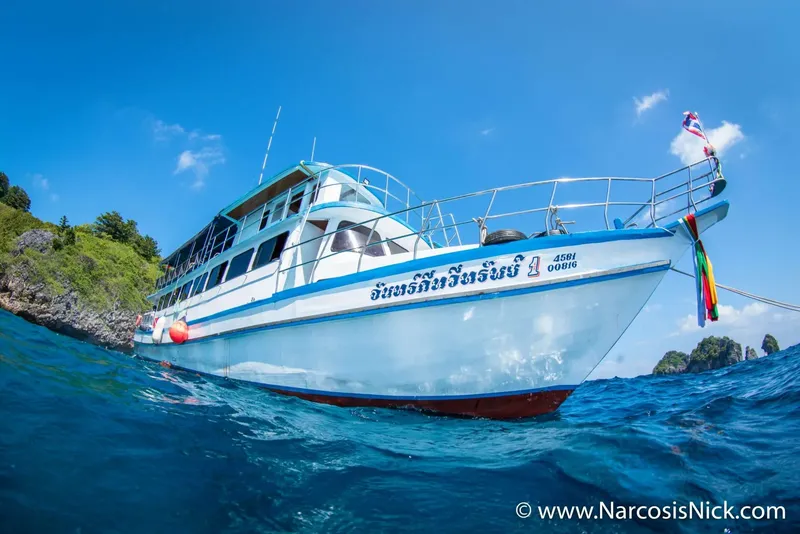 Bateau de plongée blanc et bleu naviguant dans une eau turquoise claire