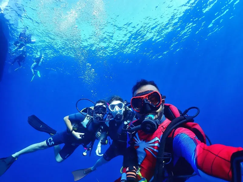 Plongeurs souriants sous l'eau, avec équipement complet et visibilité claire