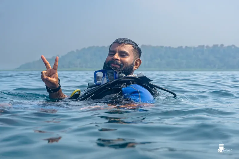 Plongeur souriant faisant un signe de la main dans l'eau