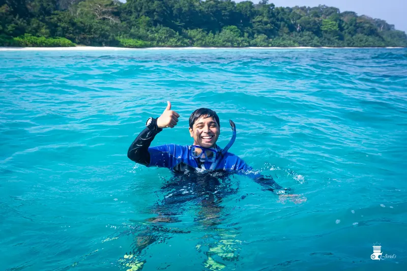 Un plongeur souriant fait un signe de pouce levé dans l'eau turquoise