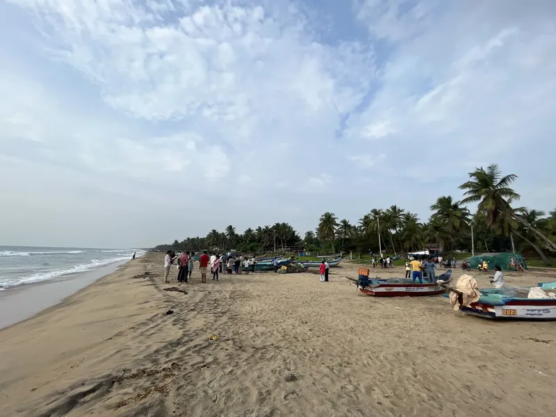 Plage avec plusieurs personnes et des bateaux de pêche colorés échoués