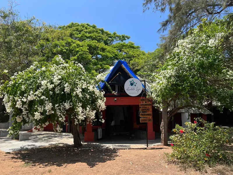 Façade d'un bâtiment rouge avec un toit bleu et des arbres fleuris
