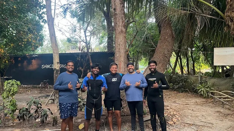 Groupe de cinq personnes souriantes, certaines en combinaison de plongée, font le signe ok