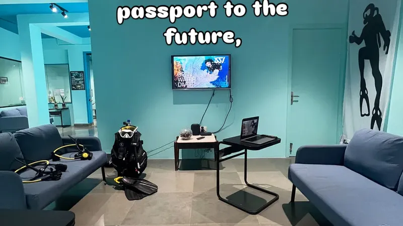 Salle d'attente avec équipement de plongée, canapés et écran affichant une image sous-marine