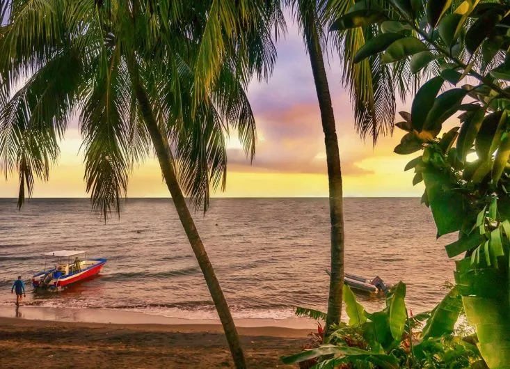 Plage tropicale avec un bateau de pêche et des personnes au bord de l'eau