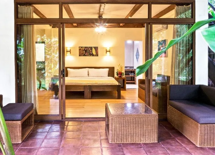 Intérieur d'une chambre avec salon ouvert sur une terrasse ombragée