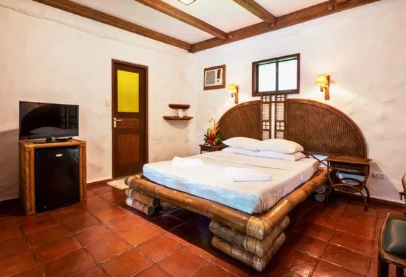 Chambre d'hôtel avec lit en bambou, télévision et décoration tropicale