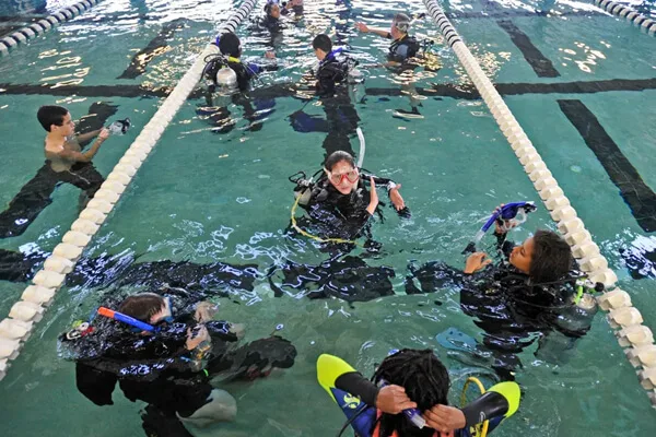 Groupe de personnes en combinaison de plongée dans une piscine