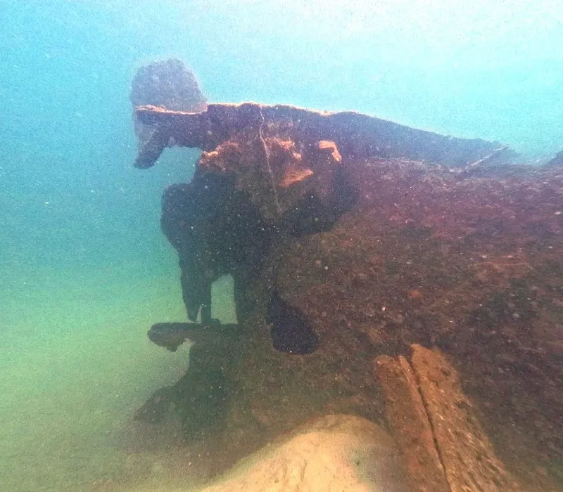 Epave rouillée sous l'eau, structure métallique et sable au fond marin