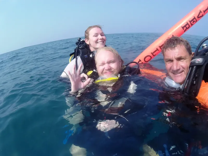Trois plongeurs souriants en surface avec leur équipement complet