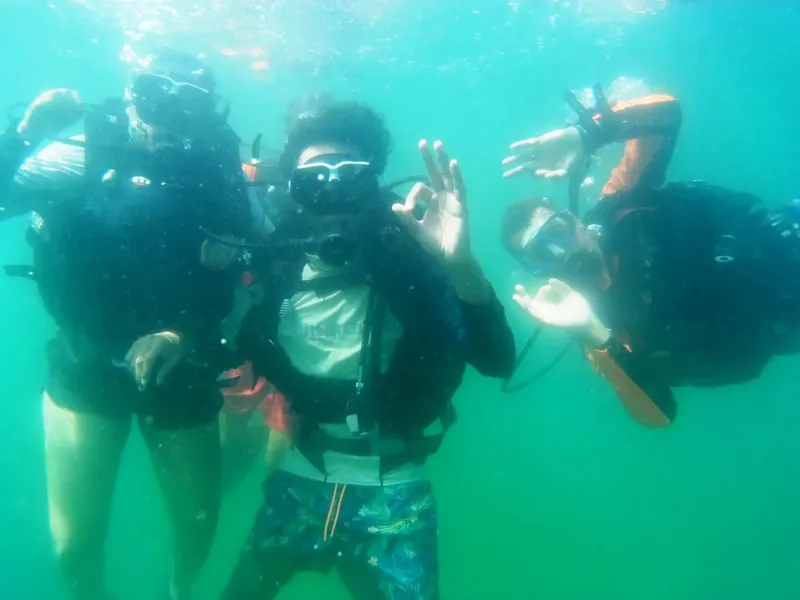 Trois plongeurs souriants font des signes de paix sous l'eau