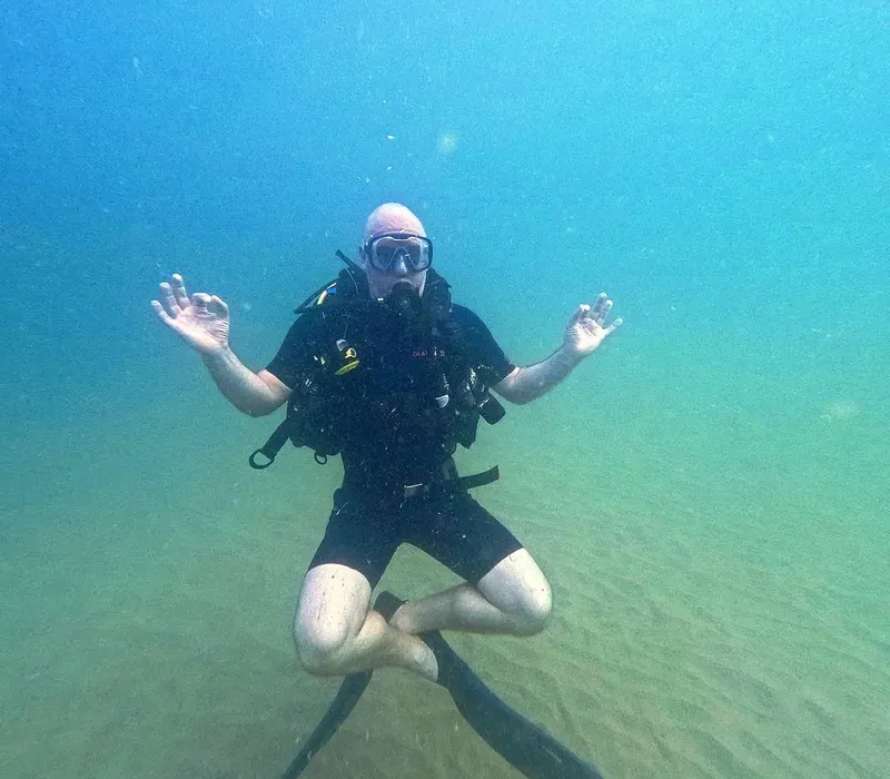 Plongeur en position de yoga sous l'eau, détendu et souriant