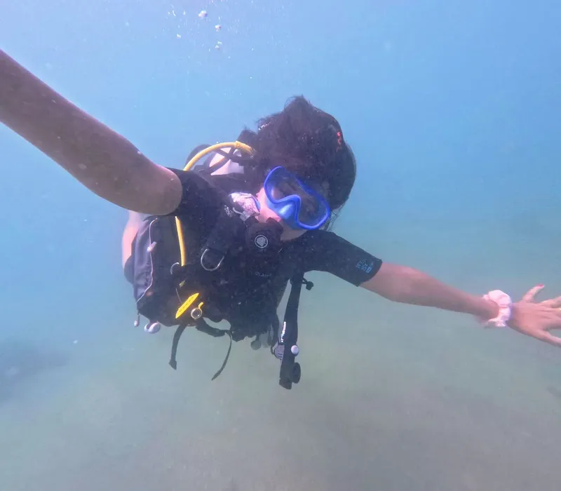 Plongeuse souriante avec équipement complet, vue en plongée sous-marine