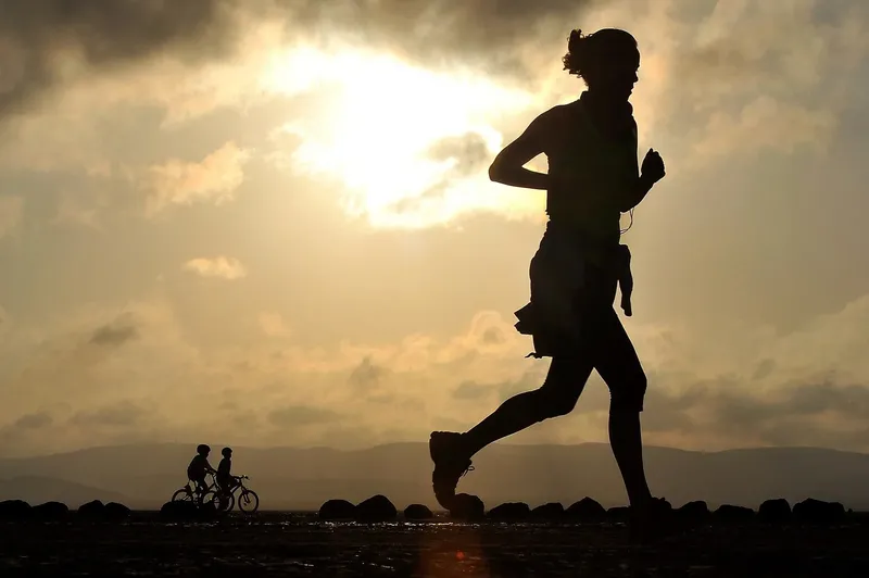 Silhouette d'une personne courant au lever ou coucher du soleil