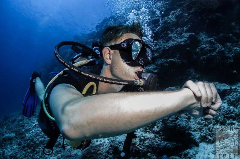 Plongeur regardant vers la caméra, équipé, dans un environnement sous-marin bleu