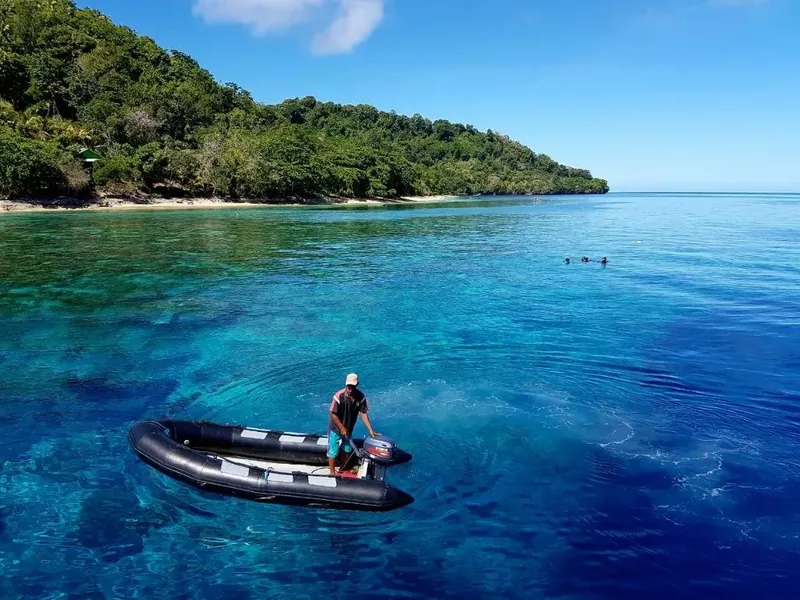 Homme conduisant un bateau pneumatique sur une mer turquoise claire