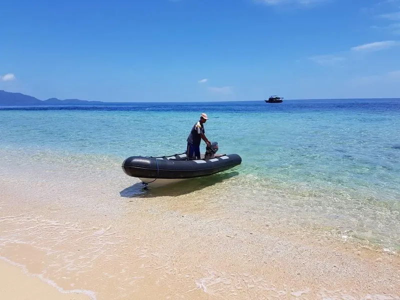 Homme préparant un bateau pneumatique sur une plage tropicale ensoleillée