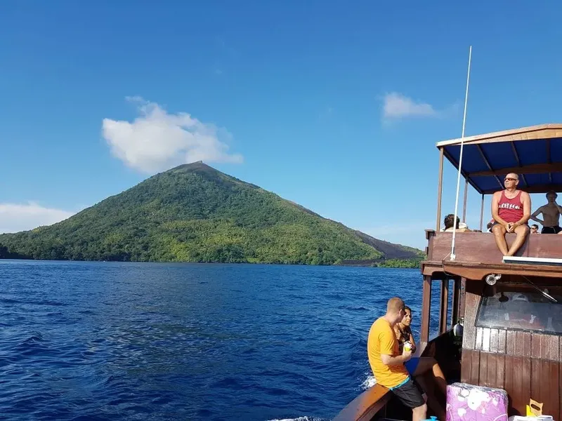 Personnes sur un bateau en mer devant une île volcanique