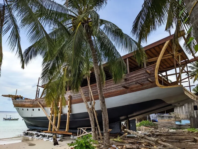 Bateau traditionnel échoué sur une plage tropicale avec cocotiers