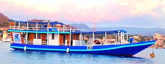 Bateau de plongée bleu et blanc amarré dans une baie ensoleillée